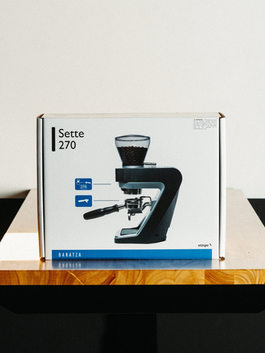 Box of a Baratza Sette 270 coffee grinder on a wooden surface with a white background